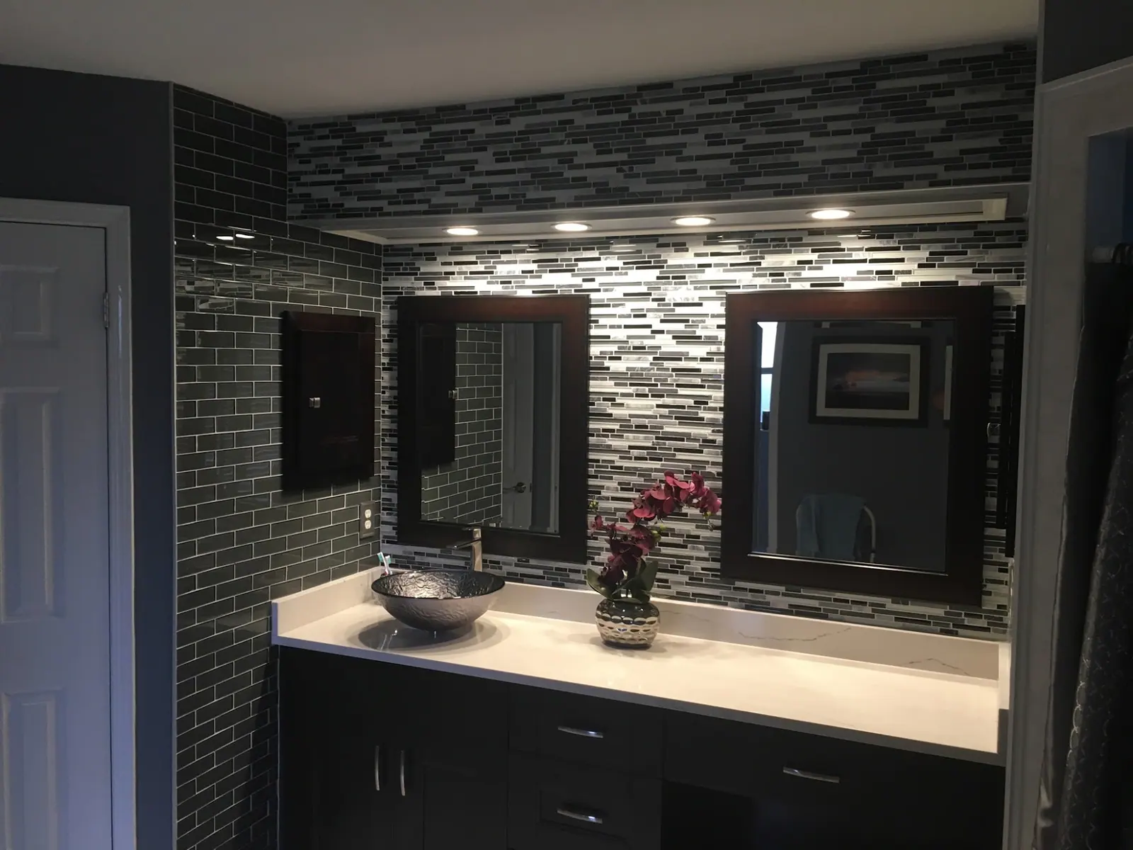 Bathroom vanity with mirrors and a mosaic tile wall