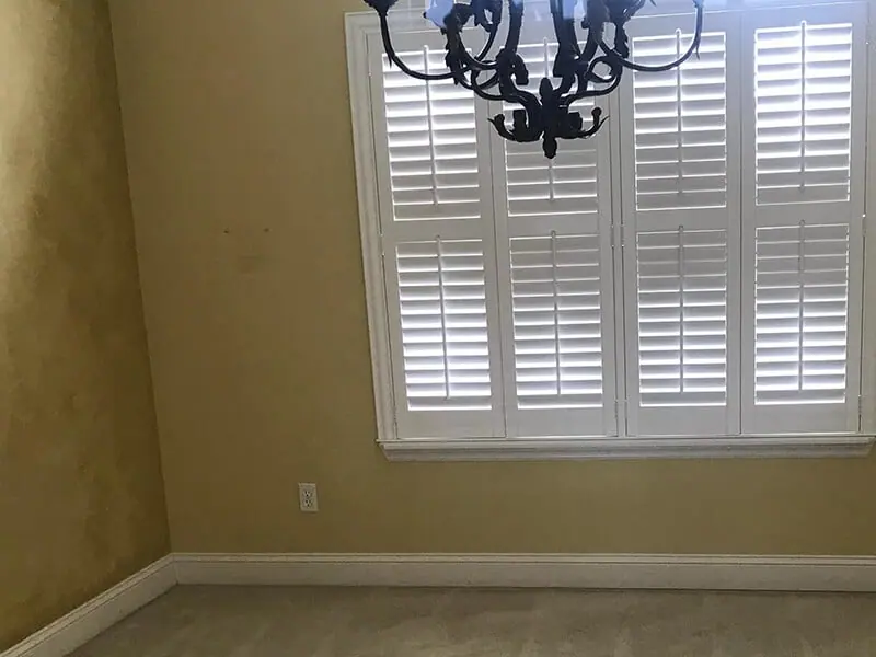 Room corner with a shuttered window and a tan wall